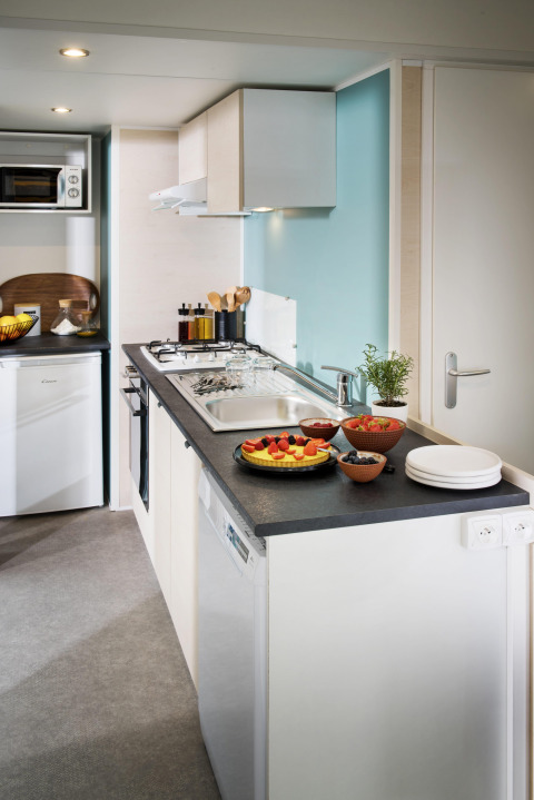 Moderne keuken in Stacaravan Family op Flower Camping Au Bois Des Biches, Frankrijk, met fruit en servies.