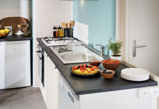 Moderne keuken in Stacaravan Family op Flower Camping Au Bois Des Biches, Frankrijk, met fruit en servies.