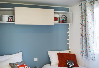 Kinderkamer met twee aparte bedden, kleurrijke kussens en speelgoed in Stacaravan Family, Flower Camping Au Bois Des Biches.
