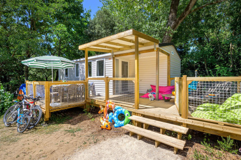 Vue extérieure de Stacaravan Family avec terrasse en bois et vélos au Flower Camping Au Bois Des Biches, France.