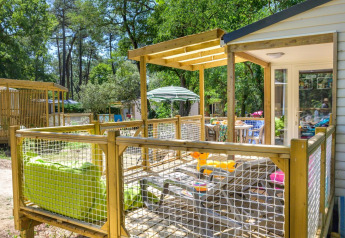Terrazza esterna di uno chalet con spiedini alla griglia, immersa nel verde bosco in Francia.