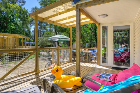 Wooden terrace with inflatable duck, lounge chair and outdoor dining at Stacaravan Family, Flower Camping Au Bois Des Biches, France.