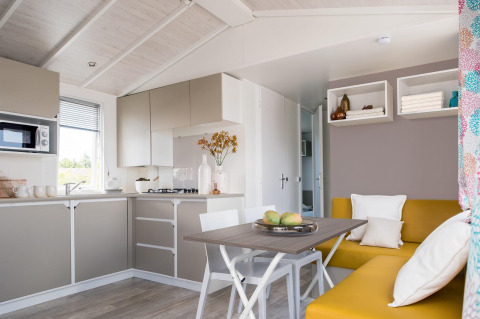 Bright modern kitchen and dining area in Stacaravan Family chalet at Flower Camping Au Bois Des Biches, France.