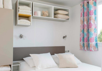 Modernes Chalet-Schlafzimmer mit hellen Farben, Doppelbett, offenen Regalen und bunten Vorhängen in Frankreich.
