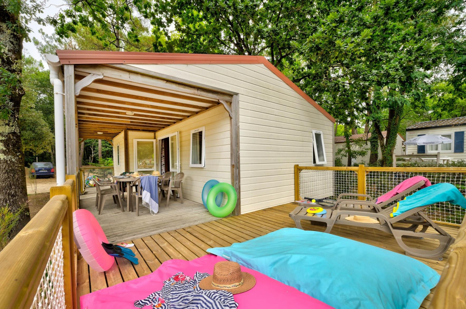 Buitenterras van Cottage Family bij Flower Camping Au Bois Des Biches, Frankrijk, met ligstoelen en tafel.