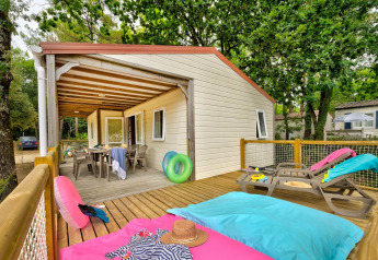 Terrasse des Cottage Family im Flower Camping Au Bois Des Biches, Frankreich, mit Liegestühlen und Esstisch.