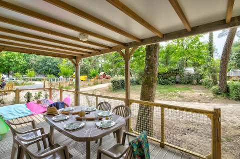 Overdekt houten terras bij Cottage Family, Flower Camping Au Bois Des Biches in Frankrijk, met eettafel.