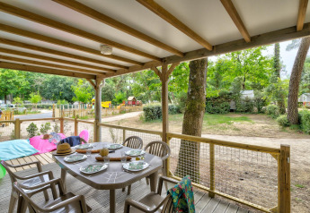 Terraza techada del Cottage Family en Flower Camping Au Bois Des Biches, Francia, con mesa puesta para comer.