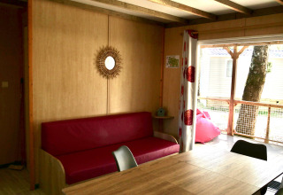 Binnenzicht van Cottage Family in Flower Camping Au Bois Des Biches met rode sofa en houten tafel.