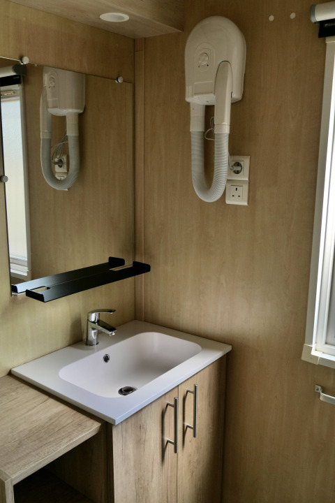 Badkamer van de Cottage Family bij Flower Camping Au Bois Des Biches, met wastafel, spiegel en haardroger.