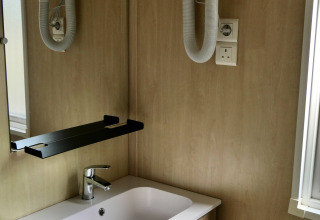 Badkamer van de Cottage Family bij Flower Camping Au Bois Des Biches, met wastafel, spiegel en haardroger.