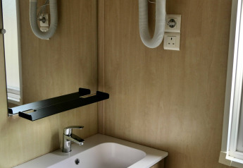 Badezimmer im Chalet Cottage Family bei Flower Camping Au Bois Des Biches mit Waschbecken und Haartrockner.