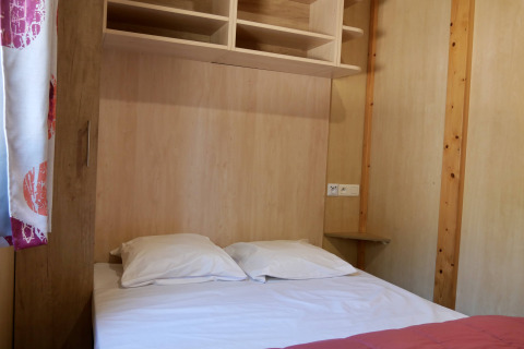 Slaapkamer met tweepersoonsbed en rekken in Cottage Family op Flower Camping Au Bois Des Biches, Frankrijk