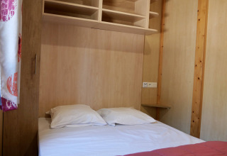 Slaapkamer met tweepersoonsbed en rekken in Cottage Family op Flower Camping Au Bois Des Biches, Frankrijk
