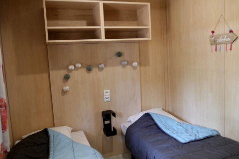 Twee enkele bedden in een knusse houten chaletkamer van Cottage Family, Flower Camping Au Bois Des Biches in Frankrijk.