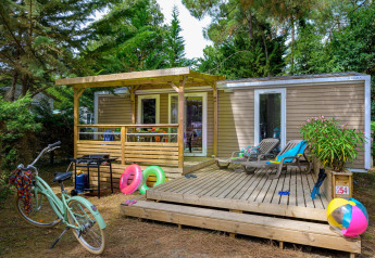 Außenansicht des Stacaravan Premium+ Chalets bei Flower Camping Au Bois Des Biches mit Terrasse und Sommeraccessoires.