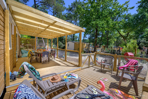 Überdachte Holzterrasse mit Gartenmöbeln bei Stacaravan Family im Flower Camping Au Bois Des Biches, Frankreich.