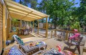 Überdachte Holzterrasse mit Gartenmöbeln bei Stacaravan Family im Flower Camping Au Bois Des Biches, Frankreich.