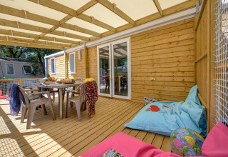 Terraza de madera con mesa, sillas y pufs en Stacaravan Family, Flower Camping Au Bois Des Biches, Francia.
