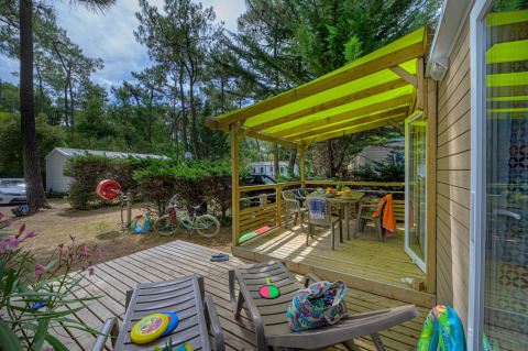 Buiten terras bij Stacaravan Premium+ in Flower Camping Au Bois Des Biches met stoelen en kinderspeelgoed.