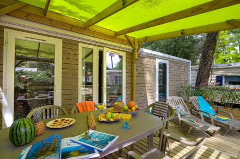 Buitenterras van Stacaravan Premium+ bij Flower Camping Au Bois Des Biches met tafel en ligstoelen.