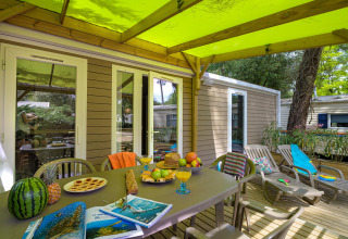 Terrasse des Stacaravan Premium+ im Flower Camping Au Bois Des Biches mit Obst, Snacks und Liegestühlen.