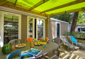 Terrasse des Stacaravan Premium+ im Flower Camping Au Bois Des Biches mit Obst, Snacks und Liegestühlen.