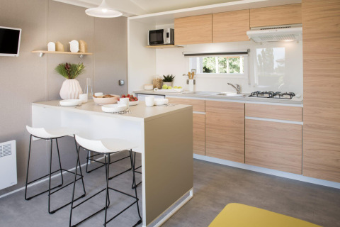 Moderne keuken in de Stacaravan Premium+ bij Flower Camping Au Bois Des Biches met houten kasten en eiland.