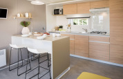Cucina moderna nello Stacaravan Premium+ al Flower Camping Au Bois Des Biches con isola e pensili in legno.