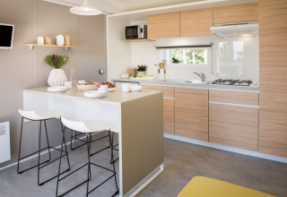 Moderne keuken in de Stacaravan Premium+ bij Flower Camping Au Bois Des Biches met houten kasten en eiland.