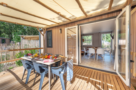 Buitenterras met eettafel bij Stacaravan Garden, Flower Camping Au Bois Des Biches in Frankrijk, zonnige dag.