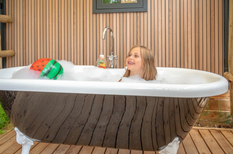 Bambina che si diverte in un bagno di schiuma in una vasca da esterno presso Stacaravan Garden, Flower Camping Au Bois Des Biches, Francia.