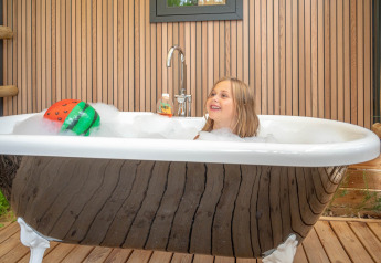 Bambina che si diverte in un bagno di schiuma in una vasca da esterno presso Stacaravan Garden, Flower Camping Au Bois Des Biches, Francia.