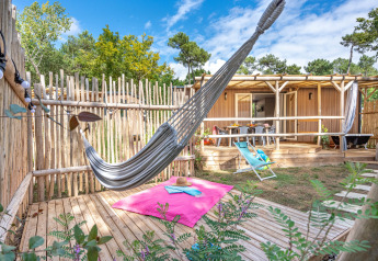 Chalet de jardin élégant avec hamac et terrasse ensoleillée au Flower Camping Au Bois Des Biches, France.