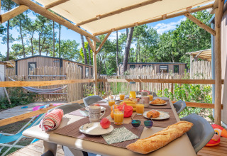 Überdachte Terrasse mit Frühstückstisch am Stacaravan Garden im Flower Camping Au Bois Des Biches, Frankreich.