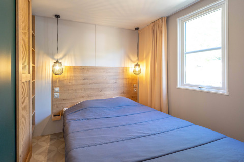 Moderne slaapkamer in Stacaravan Garden op Flower Camping Au Bois Des Biches met groot bed en raam.