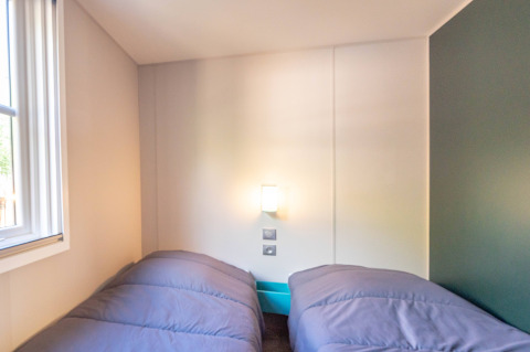 Slaapkamer in Stacaravan Garden bij Flower Camping Au Bois Des Biches in Frankrijk met twee aparte bedden.