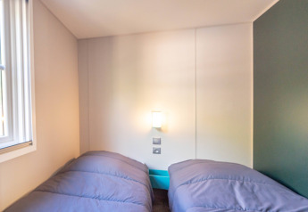 Slaapkamer in Stacaravan Garden bij Flower Camping Au Bois Des Biches in Frankrijk met twee aparte bedden.