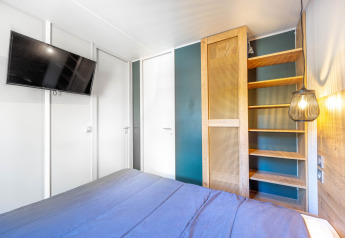 Dormitorio luminoso en Stacaravan Garden en Flower Camping Au Bois Des Biches con televisor y estantería.
