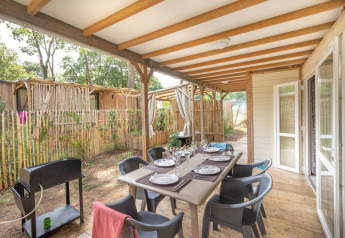 Overdekt terras met eettafel bij Cottage Garden, Flower Camping Au Bois Des Biches, Frankrijk, klaar voor gebruik.