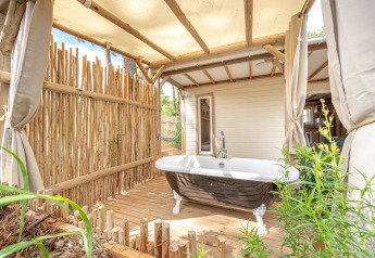 Buitenbad op houten terras met bamboe omheining bij Cottage Garden, Flower Camping Au Bois Des Biches, Frankrijk.