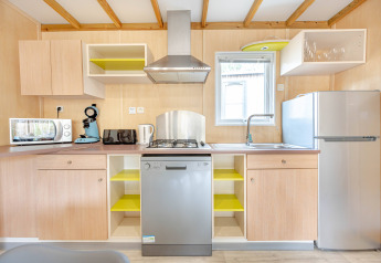 Moderne keuken met houten kasten, vaatwasser, gasfornuis, gootsteen, koelkast en keukenapparaten.