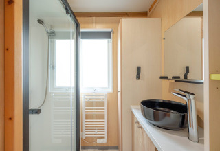 Baño moderno con ducha, lavabo negro y decoración de madera clara en Cottage Garden, Flower Camping Au Bois Des Biches, Francia.