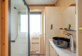 Baño moderno con ducha, lavabo negro y decoración de madera clara en Cottage Garden, Flower Camping Au Bois Des Biches, Francia.