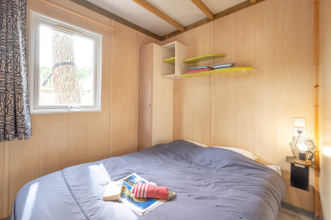 Dormitorio con cama doble, ventana y estanterías en Cottage Garden de Flower Camping Au Bois Des Biches, Francia.