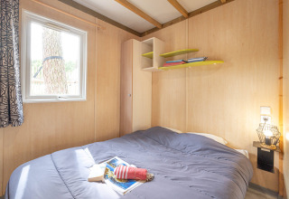 Dormitorio con cama doble, ventana y estanterías en Cottage Garden de Flower Camping Au Bois Des Biches, Francia.