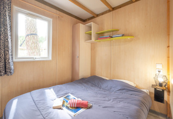 Slaapkamer met dubbel bed, raam en rekken in Cottage Garden bij Flower Camping Au Bois Des Biches, Frankrijk.