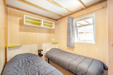 Dormitorio luminoso en Cottage Garden en Flower Camping Au Bois Des Biches, Francia, con dos camas individuales.