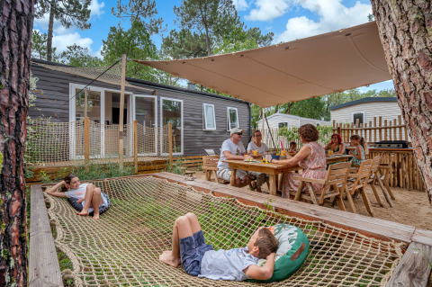 Family relaxing and dining outdoors at Stacaravan Tribu at Flower Camping Au Bois Des Biches in France.