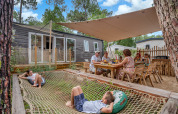 Famille se relaxant et dînant en plein air au Stacaravan Tribu du Flower Camping Au Bois Des Biches en France.
